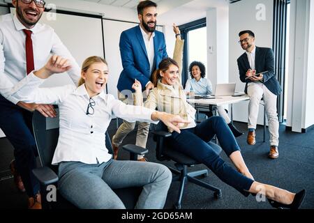 Junge Geschäftsleute im Büro, die mit einem unbändigen Humor Stühle schieben Stockfoto
