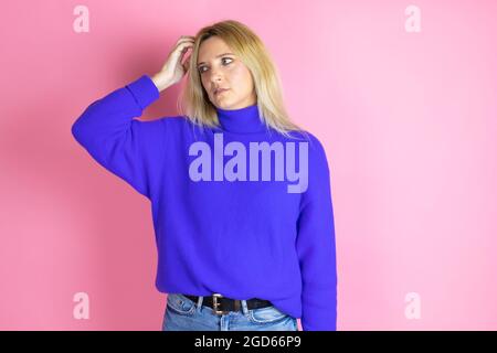 Junge schöne Frau trägt lässigen Pullover über isoliert rosa Hintergrund verwirren und fragen sich über Frage. Unsicher mit Zweifel, mit der Hand denken Stockfoto