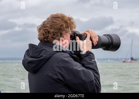 Mann mit einer Kamera mit langem Objektiv, Paparazzi mit Teleobjektiv an der Kamera, Teleobjektiv für DSLR-Kamera, Fotograf mit langem Objektiv an der Kamera. Stockfoto