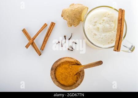 Kurkuma-Latte mit Gewürzen, Nelken, Kurkuma-Pulver, Zimtstange, Ingwer auf weißem Hintergrund Stockfoto