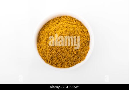 RAS el hanout marokkanisches Gewürzpulver. RAS el hanout in weißer Schale, auf weißem Hintergrund. Marokkanische Gewürze Stockfoto