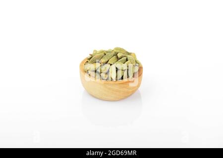 Kardamom, Kardamom-Samen, grünes Kardamom. Makroaufnahme, Kardamom-Samen in Holzschale, auf weißem Hintergrund. Stockfoto