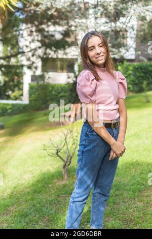 Vertikales Porträt eines Teenagers aus Latina, das lächelt und die Kamera im Freien anschaut Stockfoto