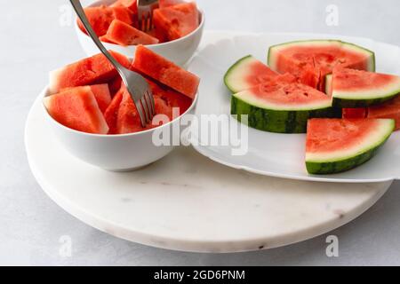 Frische Wassermelonenscheiben schließen sich in einer Schüssel auf einem Marmorbrett aus. Nachtisch, Obstsalat Stockfoto