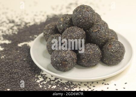 Traditionelle indische Süßbälle aus Sesamsamen, Jaggery und Kokosnuss, allgemein bekannt als Til ke laddu oder Sesam-ladoos. Aufgenommen auf weißem Hintergrund Stockfoto