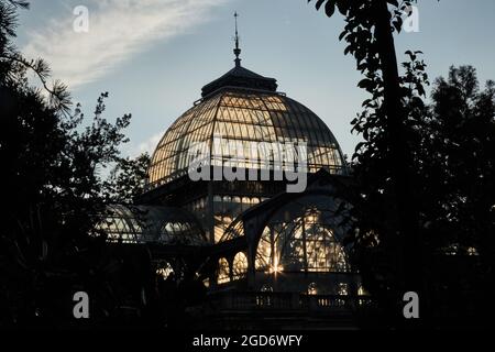 Die Abendsonne scheint durch die Scheiben der Kuppeln eines Glas- und Metallpalastes in einem Park. Horizontale Fotografie. Stockfoto