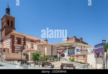 Panoramablick auf den Kirchplatz der Stadt La Calahorra mit einem Brunnen, Pflanzen, Bänken und dem Schloss von La Calahorra im Hintergrund auf t Stockfoto