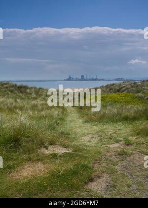 Das skelettartige Geschoss von Redcar Steelworks in Silhouette, zwischen Dünen auf der Nordseite der Tees, sonnenbeschienenen unter einem schweren Ufer von Wolken. Stockfoto