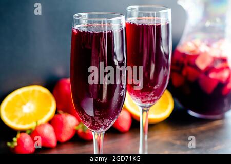 Rotwein-Champagner-Sangria in Flötengläsern serviert: Getränke aus Rotwein, Sekt und frischem Obst, serviert in Weingläsern Stockfoto