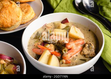 Schalen mit cremigem Chicken Eintopf serviert mit Keksen: Hühnchen- und Gemüseeintopf serviert mit Keksen auf der Seite Stockfoto