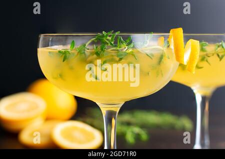 Meyer Lemon and Thyme Bees Knees Cocktails: Gin-Cocktails mit Meyer Zitronensaft und garniert mit Thymiansprigs und einem Twist Stockfoto