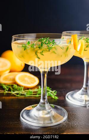 Meyer Lemon and Thyme Bees Knees Cocktails: Gin-Cocktails mit Meyer Zitronensaft und garniert mit Thymiansprigs und einem Twist Stockfoto