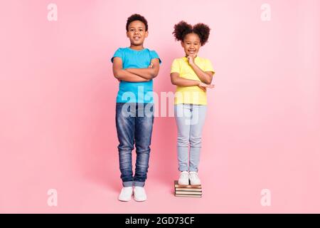 In voller Länge Körpergröße Ansicht von zwei netten fröhlichen Freunden stehen auf Buch isoliert über rosa Pastellfarben Hintergrund Stockfoto