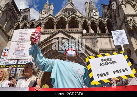 London, Großbritannien. August 2021. Ein Demonstranten, der als eine mit verbundenen Augen und blutigen Freiheitsstatue gekleidet ist, hält während des Protestes vor den königlichen Gerichtshöfen ein Plakat mit dem Titel „Free Assange, Free Press“, wo die Vorverhandlung für die US-Berufung gegen die Entscheidung, den WikiLeaks-Gründer Julian Assange nicht auszuliefern, stattfand. Kredit: SOPA Images Limited/Alamy Live Nachrichten Stockfoto