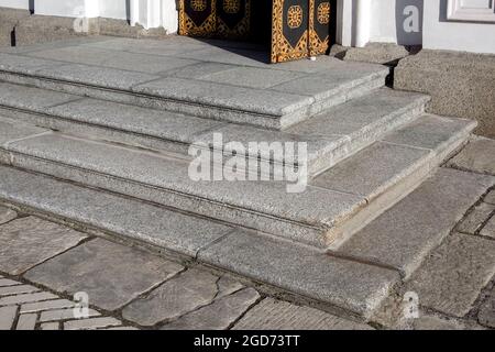 Ecke Granit Schwelle am Eingang offene Tür aus schwarzem Rost Eisen und weiße Fassade Verkleidung aus grauem Granit ein altes Retro-Gebäude Nahaufnahme Seite V Stockfoto