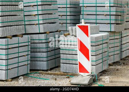 Betonkanten auf Holzpaletten stehen während der Straßenreparatur in der Stadt auf der Straße Stockfoto