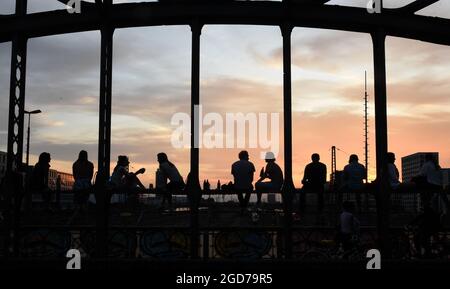 München, Deutschland. August 2021. Junge Menschen entspannen sich abends auf dem Gerüst der Hackerbrücke bei einem Drink in der Abendsonne. Quelle: Felix Hörhager/dpa/Alamy Live News Stockfoto