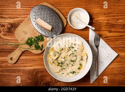 Ravioli mit Pilzen, Parmigiano, Petersilie und frischem Basilikum. Holztisch-Anordnung. Nahaufnahme. Draufsicht Stockfoto