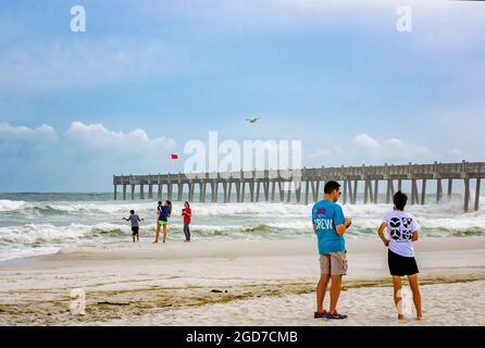 Am Pensacola Beach stehen Menschen, als vor der Ankunft des Unwandes Michael am 9. Oktober 2018 in Pensacola, Florida, eine rote Flagge weht. Stockfoto