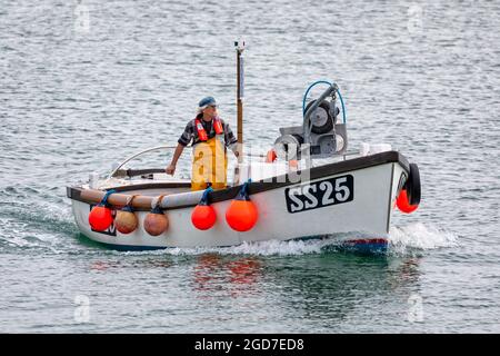 Rauchender Fischer bringt am 2 Auigust 2021 ein kleines Fischerboot an die Küste in St. Ives, Cornwall, Großbritannien Stockfoto