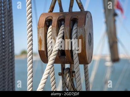 Nahaufnahme einer Dreifachrolle mit Seilen auf einem Segelschiff Stockfoto