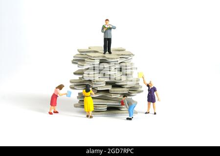 Miniatur Menschen Spielzeug Figur Fotografie. Eine Gruppe von Studenten, die über einem Puzzle-Puzzle-Stapel stehen, isoliert auf weißem Hintergrund. Bildfoto Stockfoto