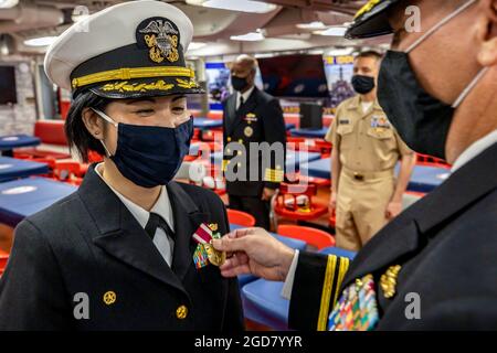 YOKOSUKA, Japan (14. April 2021) Cmdr. Diane Cua, Kommandant des Arleigh Burke-Klasse Lenkraketen-Zerstörers USS Curtis Wilbur (DDG 54), erhält die Meritorious Sevice Medal von Kapitän Chase Sergeant, Commodore von Destroyer Squadron 15, während einer Befehlswechselzeremonie. Bef. Anthony Massey wird das Kommando über Curtis Wilbur übernehmen und Cua für zukünftige Marinestreiteinsätze entlasten. Curtis Wilbur ist der Task Force 71/Destroyer Squadron (DESRON) 15 zugeordnet, der größten vorwärtseingesetzten DESRON der Marine und der wichtigsten Surface Force der US-Flotte der 7. Flotte. (USA Navy Foto von Mass Communication Sp Stockfoto