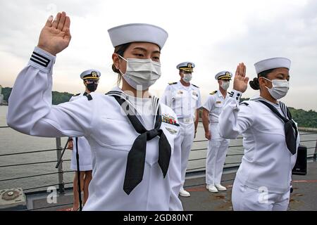 YOKOSUKA, Japan (7. Mai 2021) – Retail Specialist 3rd Class Fangfang Wen, ursprünglich aus China, links, und Retail Specialist 3rd Class Chloe Nichole Luz Rodriguez, ursprünglich aus den Philippinen, rechts, rezitieren den Schwur der Allegiance an Bord der USS Mustin (DDG 89) während einer Einbürgerung der Vereinigten Staaten von Amerika und Immigration Services (USCIS). Die Veranstaltung war die erste Einbürgerungszeremonie an Bord eines aktiven US-Navy-Schiffes während der COVID-19-Pandemie. Mustin wird nach Japan entsandt und bei Commander Fleet Activities Yokosuka (CFAY) als Teil der 7. US-Flotte stationiert. Für Stockfoto