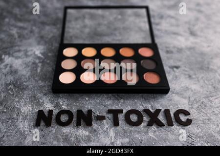 Low tox und natürliche Beauty-Produkte konzeptuelles Bild, Make-up-Palette mit ungiftigem Text auf grauem Hintergrund Stockfoto