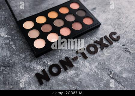 Low tox und natürliche Beauty-Produkte konzeptuelles Bild, Make-up-Palette mit ungiftigem Text auf grauem Hintergrund Stockfoto