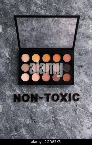 Low tox und natürliche Beauty-Produkte konzeptuelles Bild, Make-up-Palette mit ungiftigem Text auf grauem Hintergrund Stockfoto