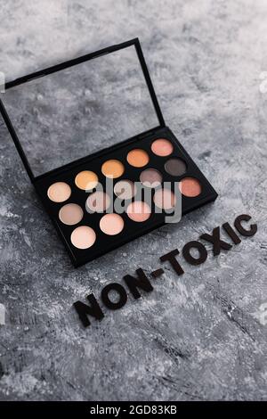 Low tox und natürliche Beauty-Produkte konzeptuelles Bild, Make-up-Palette mit ungiftigem Text auf grauem Hintergrund Stockfoto