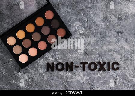 Low tox und natürliche Beauty-Produkte konzeptuelles Bild, Make-up-Palette mit ungiftigem Text auf grauem Hintergrund Stockfoto