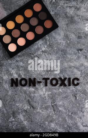 Low tox und natürliche Beauty-Produkte konzeptuelles Bild, Make-up-Palette mit ungiftigem Text auf grauem Hintergrund Stockfoto