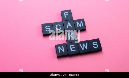 Eine Gruppe von abscheulichen Kacheln bilden Wortbetrug Fake News. Selektiver Fokus auf die Kacheln auf rosa Hintergrund isoliert Stockfoto