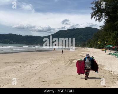 Patong, Thailand. August 2021. Eine Verkäuferin spaziert am berühmten Patong Beach auf der Insel Phuket. Trotz Coronas Modellprojekt „Sandbox“ zur Belebung des Tourismus bleiben die Sonnenliegen größtenteils leer. Seit dem Start des Modellprojekts am 1. Juli hat sich Phuket zu einem der wenigen Langstreckenziele der Welt entwickelt, an dem Menschen aus fast 70 Ländern Quarantäne-frei Urlaub machen können - solange sie vollständig geimpft sind. (An dpa-Korr: „Keine Party auf Phuket: Eine Trauminsel als Pilotprojekt“) Quelle: Carola Frentzen/dpa/Alamy Live News Stockfoto