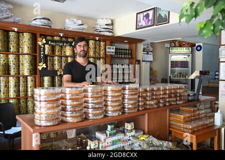 Marmaris, Türkei. August 2021. Volkan Yildiz steht an der Theke seines Ladens. Seine Familie hat seit Generationen Bienen. Die Imker kämpfen hart mit den Folgen der Waldbrände, denn viele der verbrannten Bäume sind für die Produktion von Kiefernhonig unverzichtbar. (To dpa: 'Türkische Imker in der Westtürkei verzweifelt nach Waldbränden') Quelle: Anne Pollmann/dpa/Alamy Live News Stockfoto