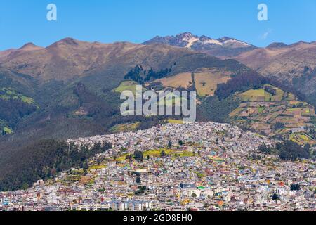 Quito-Stadt, die auf den aktiven Pichincha-Vulkanhängen erbaut wurde und Blick über den höchsten Gipfel, den Rucu Pichincha, Quito, Ecuador, bietet. Stockfoto