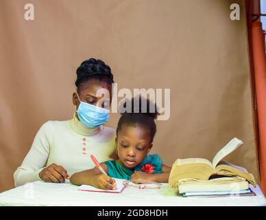 Afrikanische Lehrerin oder Mutter mit Nasenmaske, die einem kleinen Mädchen beim Studium beibringt und hilft, sich in Schule, Bildung und Karriere zu übertreffen Stockfoto