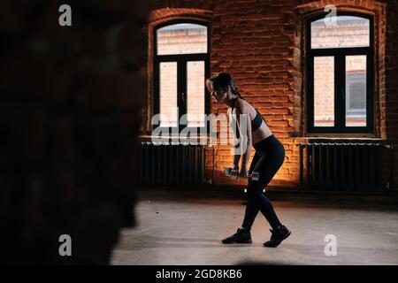 Seitenansicht der muskulösen jungen athletischen Frau mit schönen starken Körper trägt Sportbekleidung Hanteln heben. Stockfoto