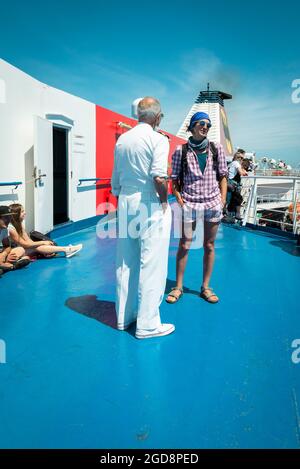 Eine Frau, die mit einem Mitglied der Besatzung auf dem Oberdeck der Fähre von Livorno nach Olbia, Sardinien, Italien, plaudert Stockfoto