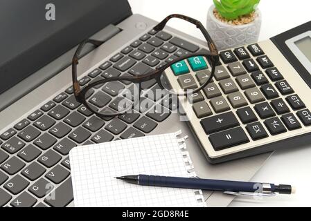 Büroarbeitsplatz mit Laptop, Brille, Notizblock, Rechner und Stift in Nahaufnahme aus dem hohen Winkel in einem Geschäfts- oder Buchhaltungs-Stillleben Stockfoto