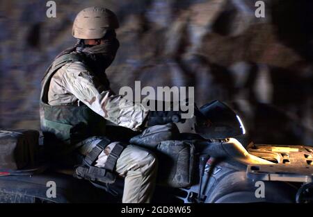 Ein Soldat der US-Armee (USA), der dem 1. Bataillon, der 3. Spezialeinsatzgruppe (SFG), zugewiesen wurde, fährt ein Geländefahrzeug (ATV) in eine Höhle, um dort am Stadtrand von Kabul, Afghanistan, nach Munitionswaffen zu suchen, während der Operation ENDURING FREEDOM. (USAF-FOTO VON SRA BETHANN HUNT 020719-F-0201H-026) Stockfoto