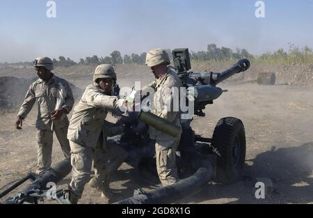 US Army (USA) Specialist (SPC) Maaka Tuionetoa, 2-319th Airborne Field Artillery Regiment, wirft ein leeres Gehäuse ab, als Soldat, der seiner Einheit zugewiesen wurde, während einer Mission auf dem internationalen Flughafen Bagdad, Irak, während der Operation IRAQI FREEDOM, den 105mm runden M119A1 105mm Lightweight Towed Howitzer feuerte. (USAF-FOTO VON MSGT JAMES M. BOWMAN 030816-F-5586B-007) Stockfoto