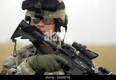 US Army (USA) Sergeant (SGT) Jon Wills, 2nd Platoon (PLT), Alpha Company (A CO), 1st Bataillon (BN), 327th Infantry (INF), 101st Airborne (ABN), Fort Campbell, Kentucky (KY), bewaffnet mit einem KAC 5.56 mm Modular Weapon System (MWS) Special Operation Specialy Modification (SOPMOD) M4, bietet Sicherheit, während sein Zug während der Operation IRAQI FREEDOM einen Traffic Control Point (TCP) durchführt, der zufällige Fahrzeuge außerhalb des Dorfes Namla, Irak, überprüft. (USAF-FOTO VON TSGT ANDY DUNAWAY 051031-F-2828D-004) Stockfoto