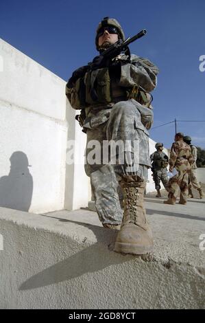 DER SERGEANT der US-Armee (SGT), Chris Chpenter, 2. Bataillon (BN), 1. Infanterie-Regiment (INF REGT), 172. Stryker Brigade Combat Team (SBCT), Fort Wainwright, Alaska (AK), sorgt für Sicherheit, während die US-Streitkräfte und die irakischen Streitkräfte während der Operation IRAQI FREEDOM über die Vorbereitungen für die bevorstehenden Wahlen in Mosul, Irak, sprechen. (USAF-FOTO VON SSGT JAMES L. HARPER JR. 051205-F-4177H-119) Stockfoto