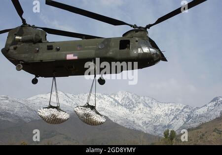 Ein Frachthubschrauber der US Army (USA) CH-47 Chinook transportiert zwei externe Lasten humanitärer Hilfsgüter (ein Teil von insgesamt 125 Tonnen), um den von mehreren schweren Schneestürmen in der Region um Muzaffarabad, Provinz Kaschmir, Pakistan (PAK) gefangenen Personen zu helfen, um die Operation LIFELINE zu unterstützen, Die von Pakistan geführte Hilfsaperation zur Unterstützung der Opfer eines verheerenden Erdbebens, das das Gebiet am 8. Oktober 2005 heimgesucht hat. (USAF-FOTO VON 1LT CHAD LEISENRING 060104-F-3228L-002) Stockfoto