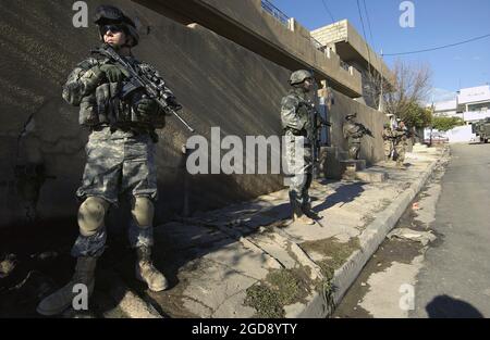 US Army (USA) Specialist Fourth Class (SPC) Shawn Aiken (links), Alpha Company (A Co), 2. Bataillon (BN), 1. Infanterie-Regiment (2/1.), 172. Stryker Brigade Combat Team (SBCT), bietet Sicherheit während einer gemeinsamen Fußpatrouille der USA und der irakischen Armee (IA) durch ein Viertel in Mosul, Provinz Ninawa, Irak (IRQ), Während der Operation IRAKISCHE FREIHEIT. (USAF-FOTO VON TSGT JOHN M. FOSTER 060121-F-2869F-004) Stockfoto