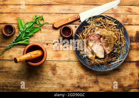 Braten in Scheiben im Heu, Schweinroulade. Gebackenes Schweinefleisch in würzigen Kräutern.Herbstfutter Stockfoto