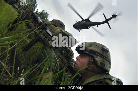 US Army (USA) Private First Class (PFC) Matthew Anderson (Front), Fallschirmjäger, Headquarters and Headquarters Company (HHC), 1. Bataillon (BN), 505. Fallschirmjäger-Infanterie-Regiment (1/505.), 82. Airborne Division (ABN), Richtet eine Perimeterverteidigung ein, nachdem er einen UH-60 Black Hawk (Blackhawk)-Hilfshubschrauber verlassen hat, während er an einer 14-tägigen Übung im Joint Readiness Training Center (JRTC) in Fort Polk, Louisiana (LA), teilnimmt, um den Einsatz seiner Einheit im Irak zur Unterstützung der Operation IRAQI FREEDOM vorzubereiten. (USAF-FOTO VON TSGT CHERIE THURLBY 060412-F-7203T-037) Stockfoto